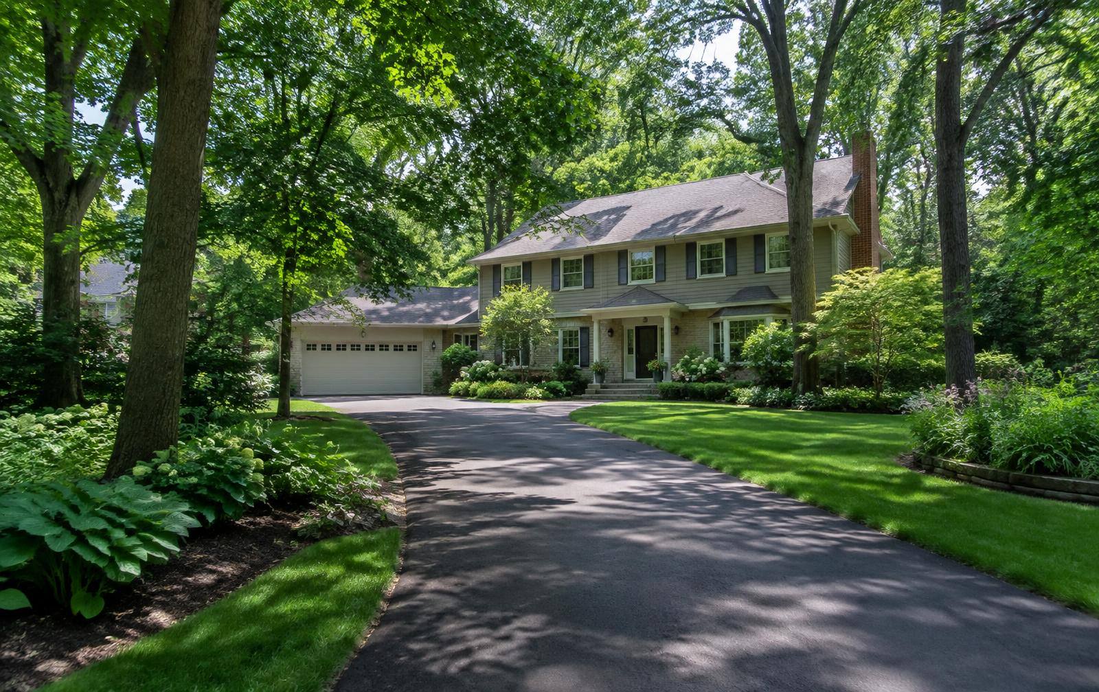 Two-story home at the end of a curving driveway surrounded by trees
